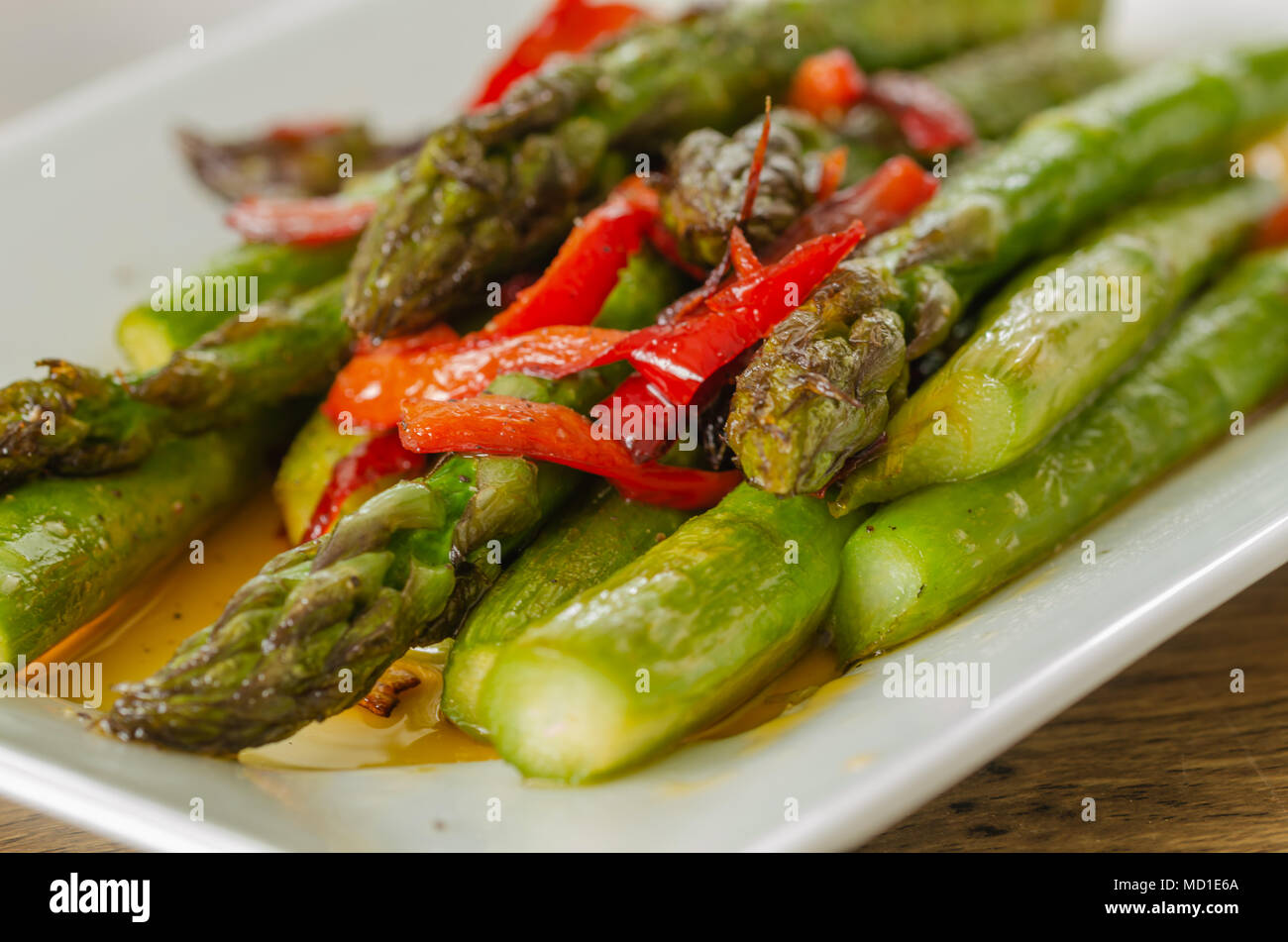 Red Pepper sauteed grüner Spargel als Salat auf dem weißen Teller serviert. Stockfoto