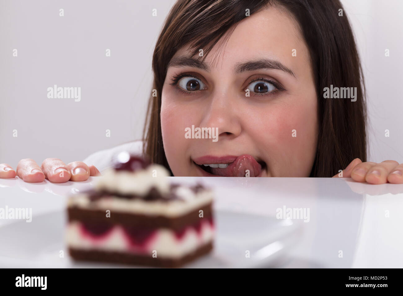 Junge Frau Lust zu essen Kuchen lecken ihre Lippen Stockfoto