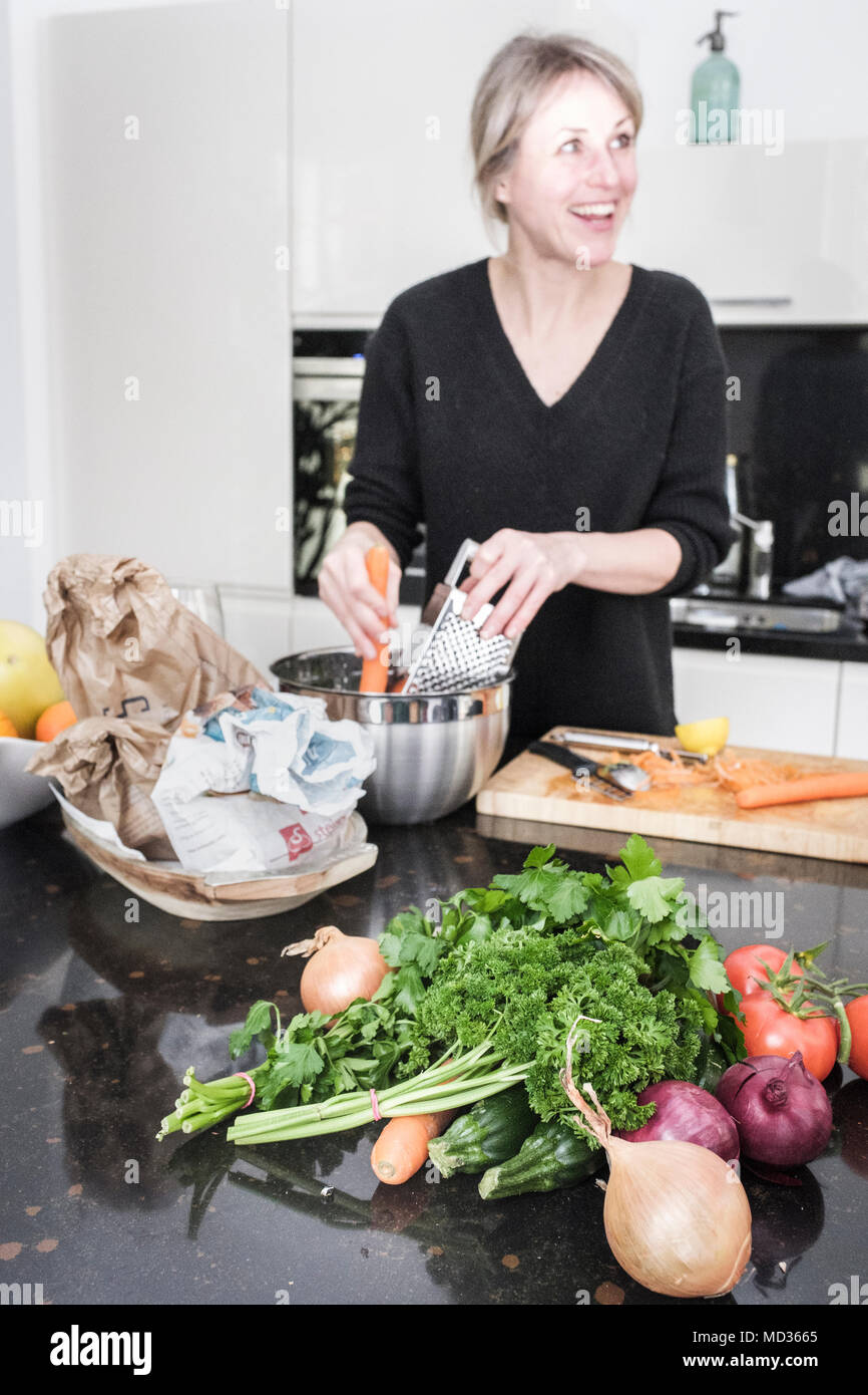 Selektiver Fokus - frische Kräuter und Gemüse auf dem Küchentisch. Gruppe von Freunden zusammen kochen beim Lachen und sich zu amüsieren. Stockfoto