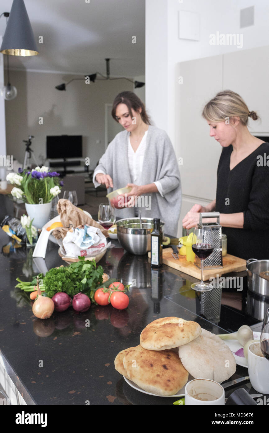 Freunde kochen zusammen vegetarisches Essen und lässig chatten .Moderne Küche Einstellung.Teilkörperaufnahme Stockfoto