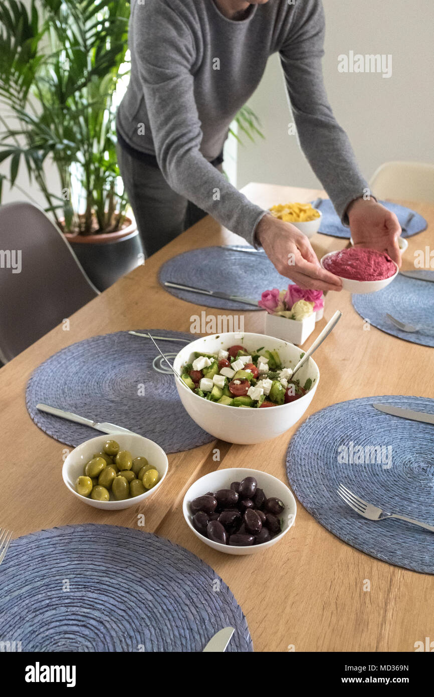 Einrichten der Tabelle für vegtarian Mahlzeit - griechischer Salat, grüne und schwarze Oliven und Rote Beete Hummus - selektive Fokus Stockfoto