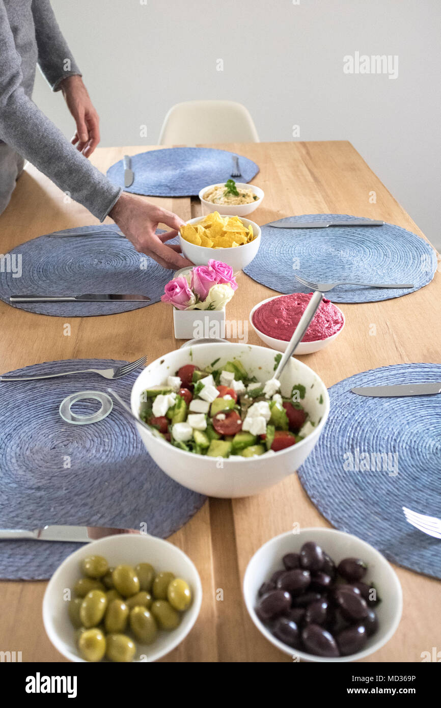 Einrichten der Tabelle für vegtarian Mahlzeit - griechischer Salat, grüne und schwarze Oliven und Rote Beete Hummus - selektive Fokus Stockfoto