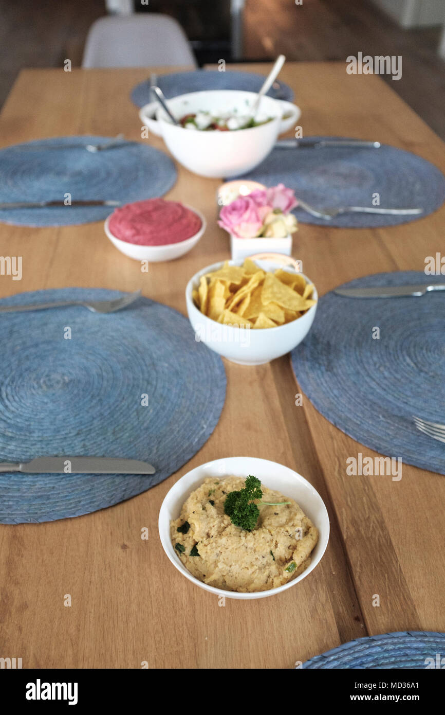 Tabelle mit vegetarischen Snacks - hummus Classic, Tortilla Chips, rote Beete Hummus, griechischer Salat Stockfoto