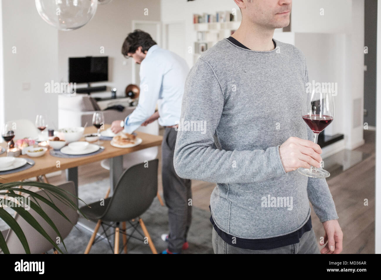 Freunde einrichten Tisch für das Mittagessen. Gruppe von Freunden beiläufig Snacking auf eine Auswahl von Lebensmitteln beim Lachen und sich zu amüsieren. Stockfoto