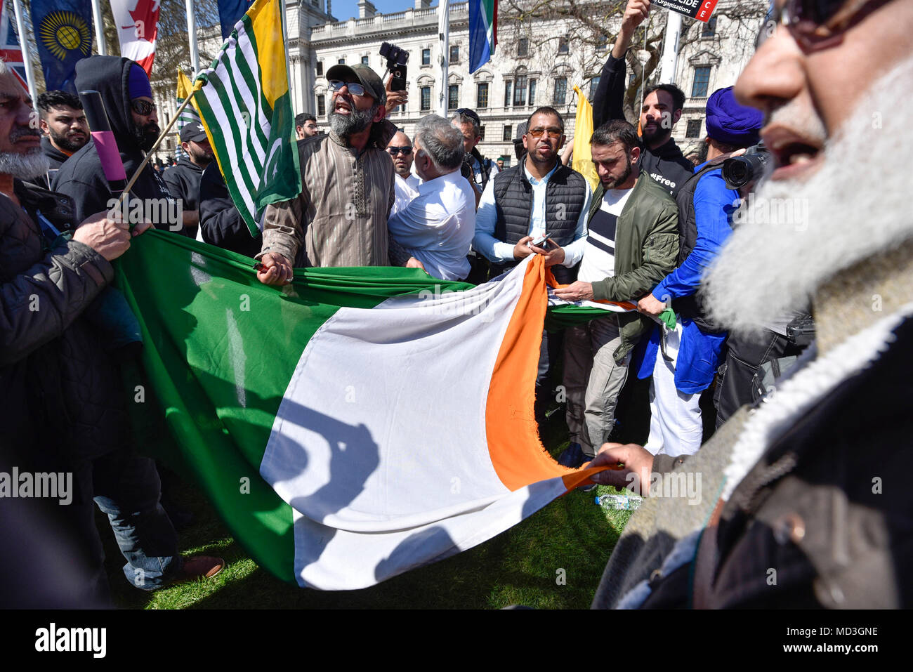 London, Großbritannien. 18. April 2018. Die indische Flagge, einer von vielen Commonwealth Flaggen im Parlament Platz fliegen, ist in Kaschmir und Siki Demonstranten aus Protest gegen das Regime des indischen Ministerpräsidenten Narendra Modi hin- und hergerissen. Sikhs, kaschmirische Muslime und andere Gruppen hatten alle ihre eigene Botschaft gegen PM Modi Wer ist zu Besuch in London teil im Commonwealth Regierungschefs Gipfel 2018 zu nehmen. Credit: Stephen Chung/Alamy leben Nachrichten Stockfoto