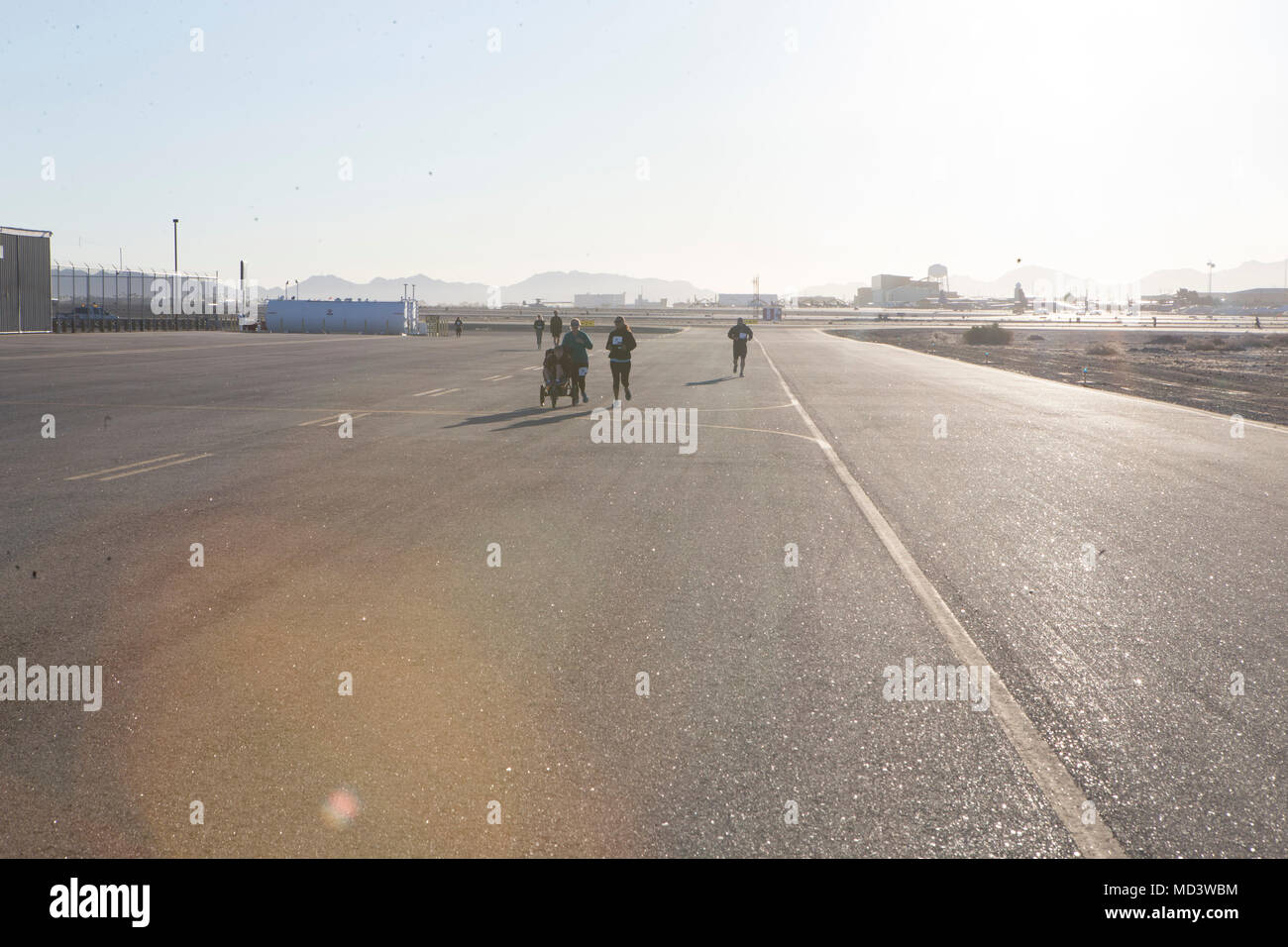 Us-Marines und Zivilisten, die Teilnahme an einem Rennen 5k auf der Marine Corps Air Station Yuma's flightline während der 2018 Wiedergabe der "Startbahn 5 k Fun Run'at MCAS Yuma, Ariz., März 17. MCAS Yuma und Marine Aviation Waffen und Taktiken Squadron 1 gehostet. Am Ende des Rennens, der kommandierende Offizier der MAWTS-1, Oberst James B. Wellons, spendete eine Überprüfung der emper Fi Fund'. (U.S. Marine Corps Foto von Cpl. Nathaniel S. McAllister/Freigegeben) Stockfoto