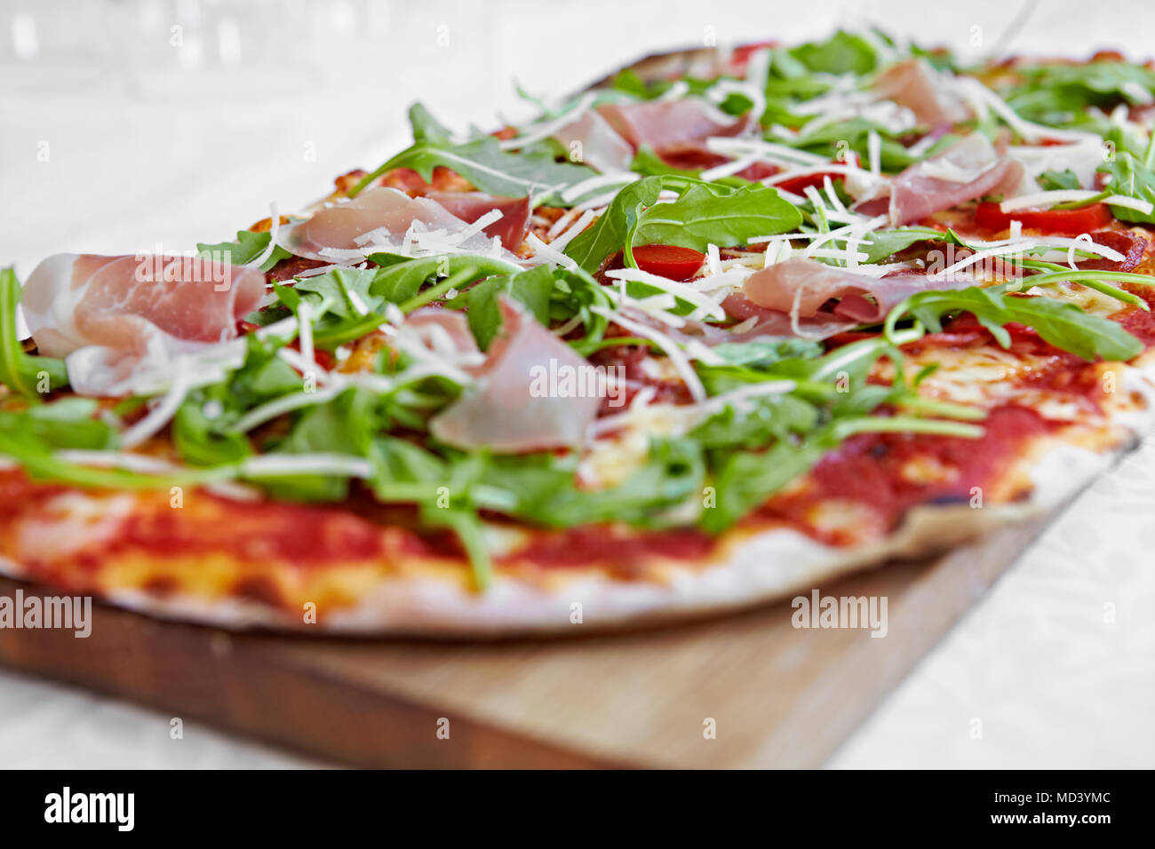 Frische Pizza mit Rucola und Parmaschinken auf Schneidebrett Stockfoto