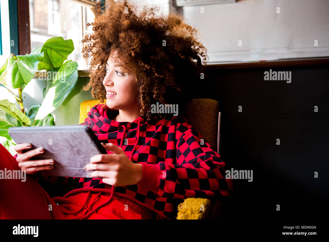 Junge Frau sitzt drinnen, mit digitalen Tablet Stockfoto