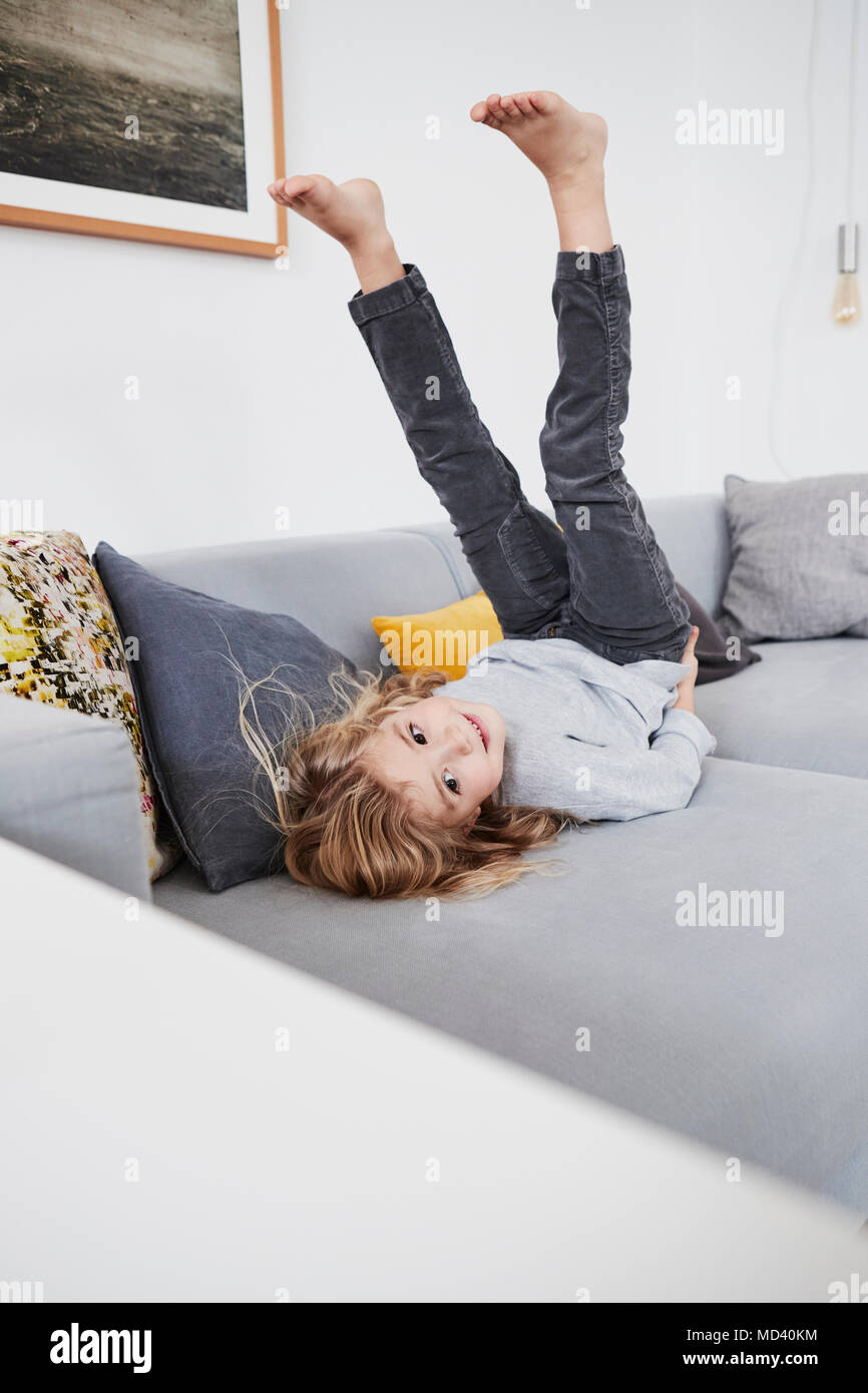 Junge Mädchen auf dem Sofa liegend mit den Beinen in der Luft Stockfoto