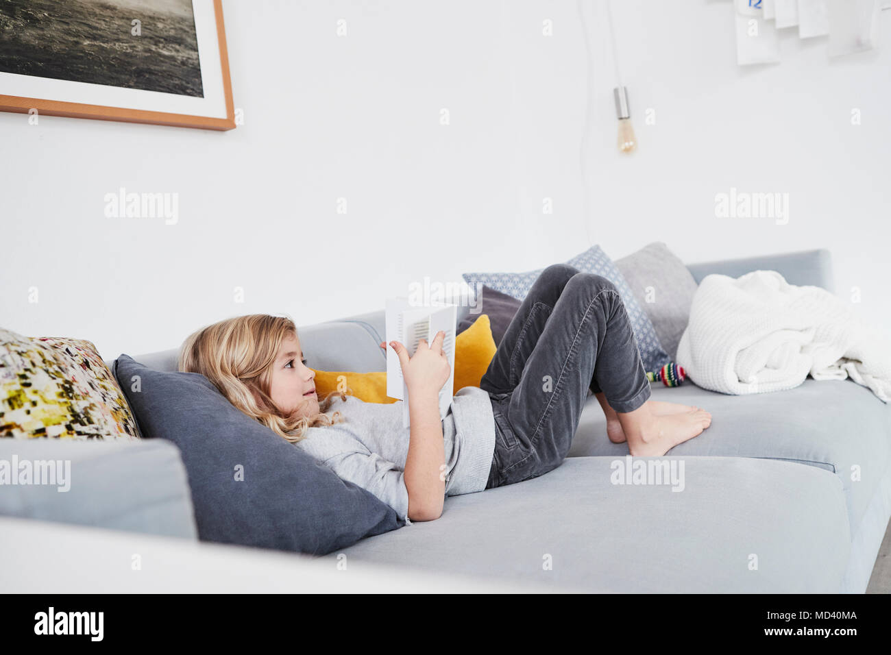 Junge Mädchen liegt auf dem Sofa, ein Buch lesen Stockfoto