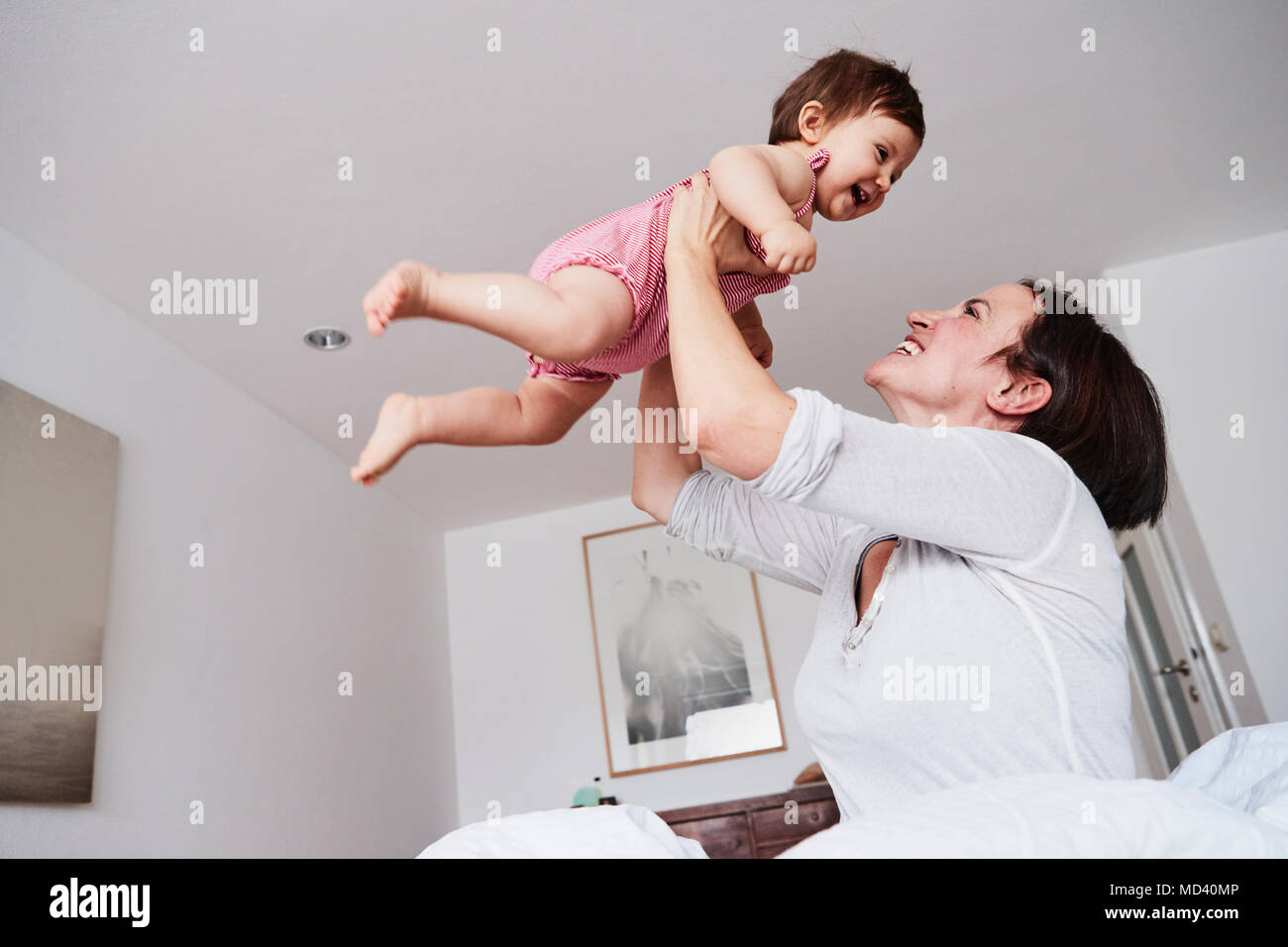 Mutter Holding baby Tochter in Luft, Low Angle View Stockfoto