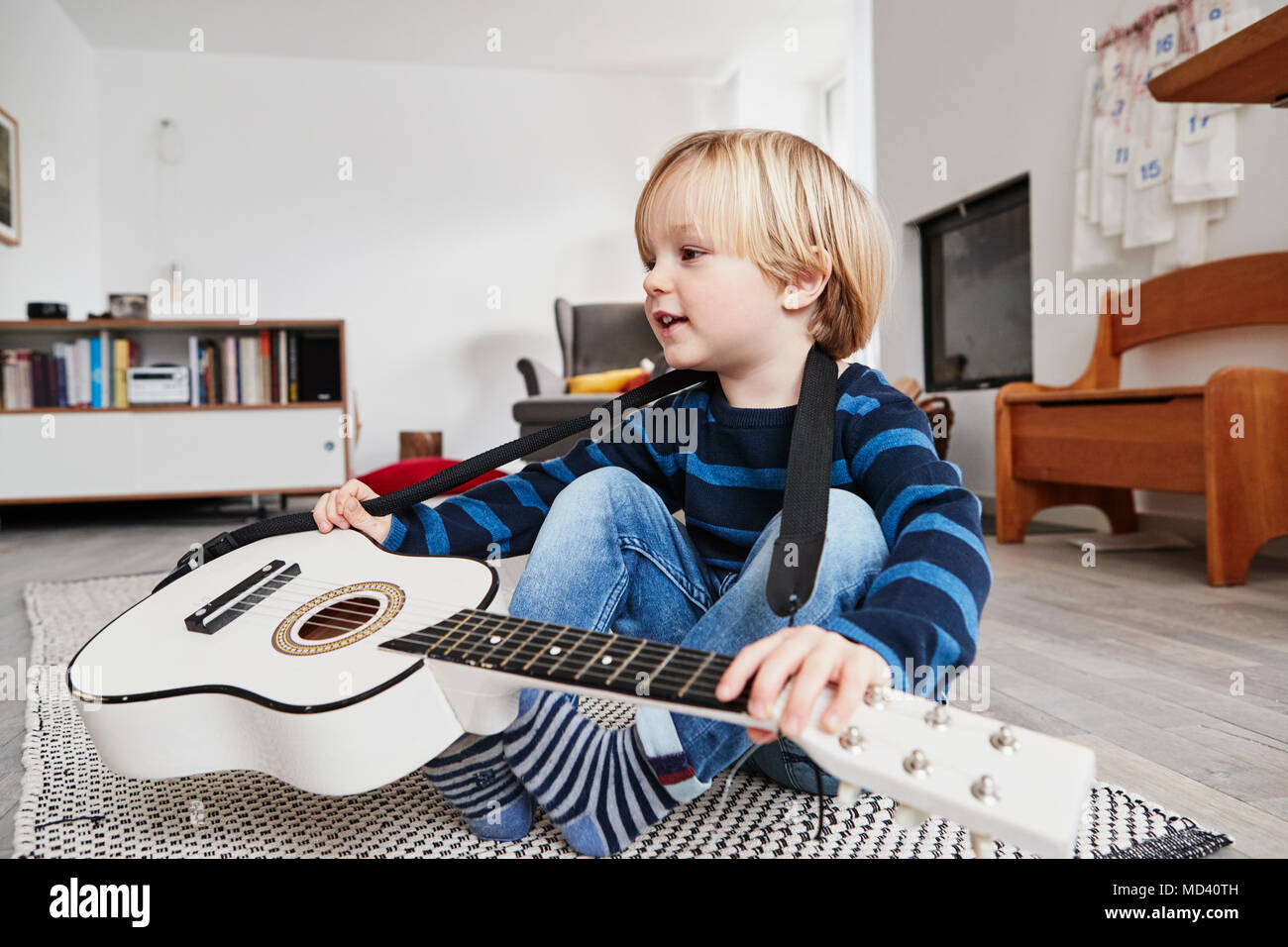 Junge Junge sitzt mit der Gitarre um den Hals Stockfoto
