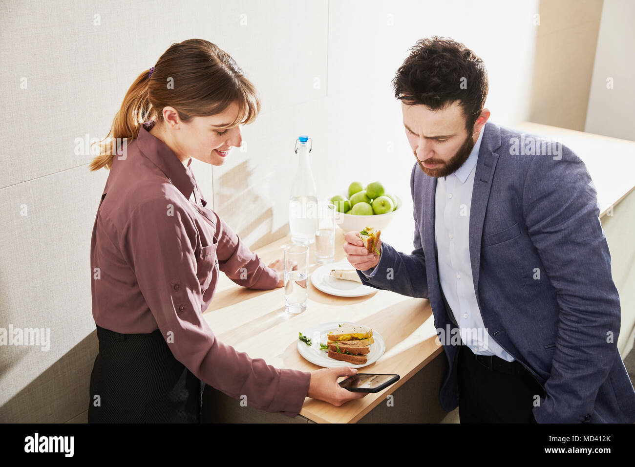 Geschäftsfrau und Mann auf Smartphone während der Mittagspause Stockfoto