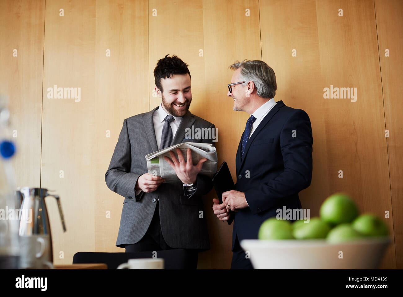 Zwei Unternehmer plaudern und lesen Zeitung in Office Sitzungssaal Stockfoto