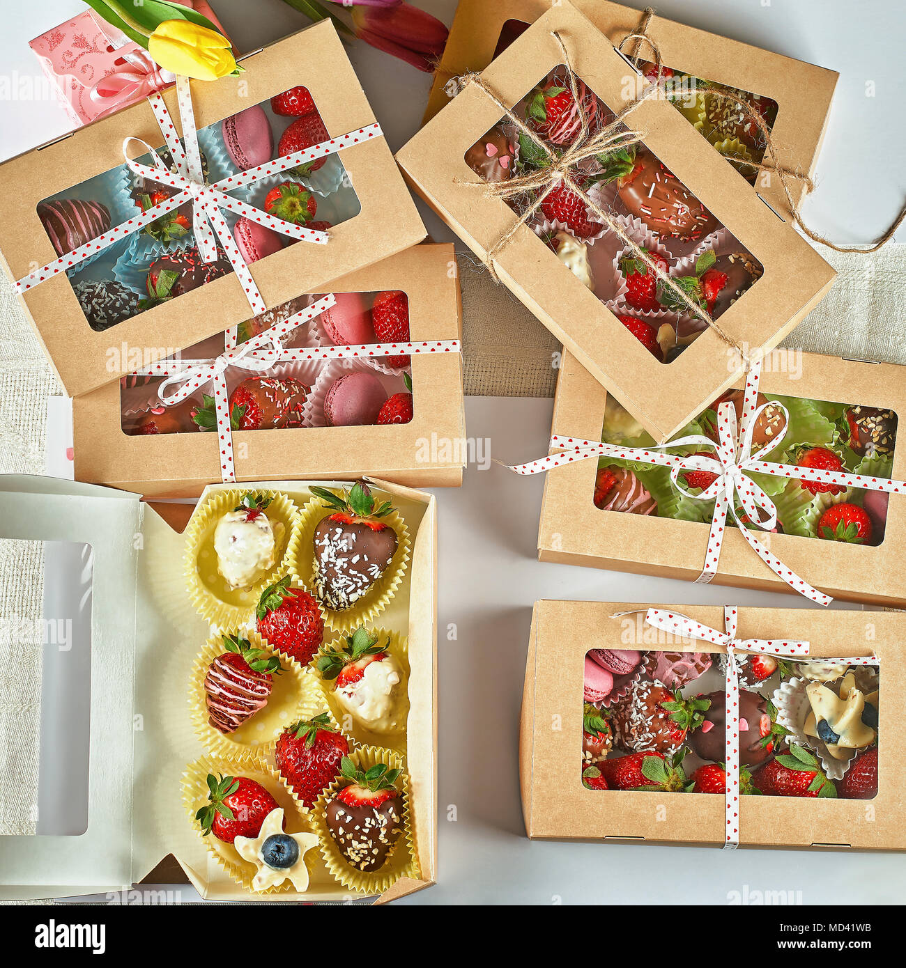 Genießbare handgemachte Geschenke, Erdbeeren in Schokolade Macaron, mit  Tulpen in einer Geschenkbox eingerichtet Stockfotografie - Alamy