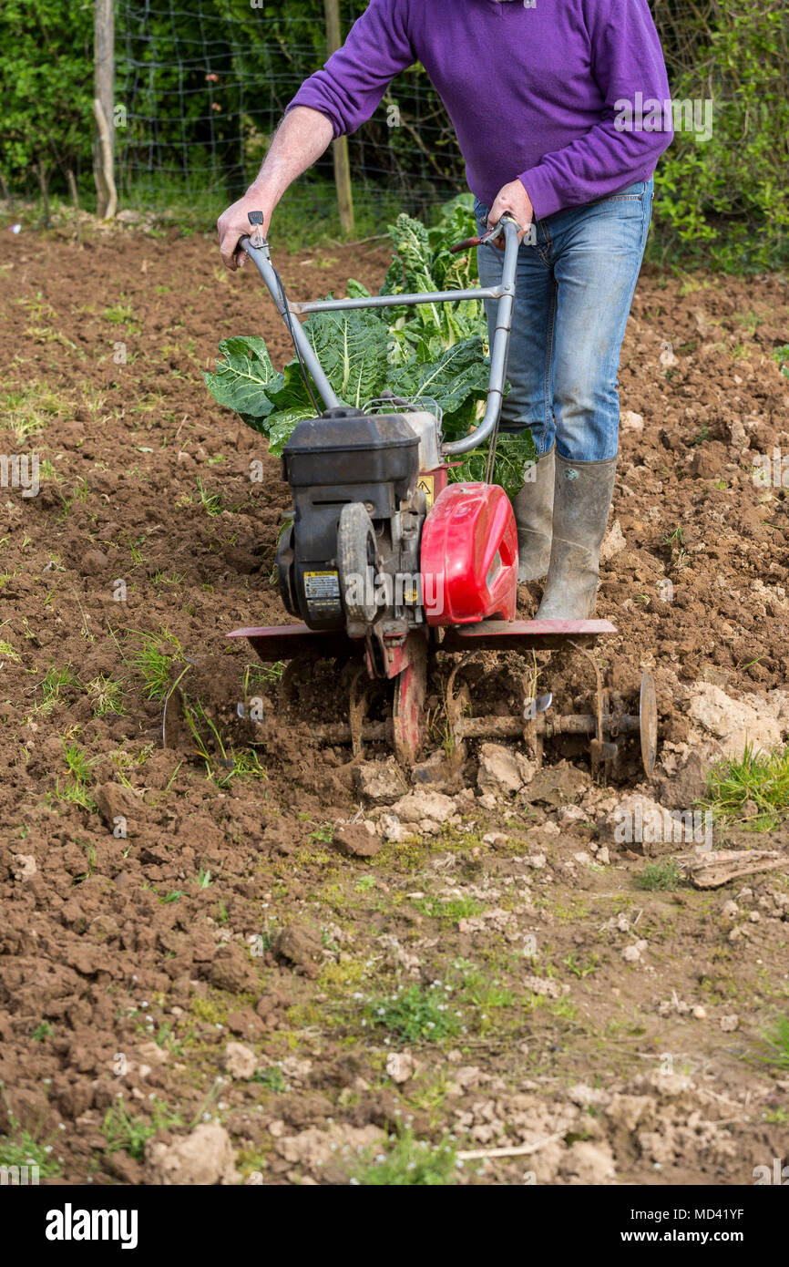 Senior Landwirt Gärtner im Garten arbeitet mit rototiller, Deichsel