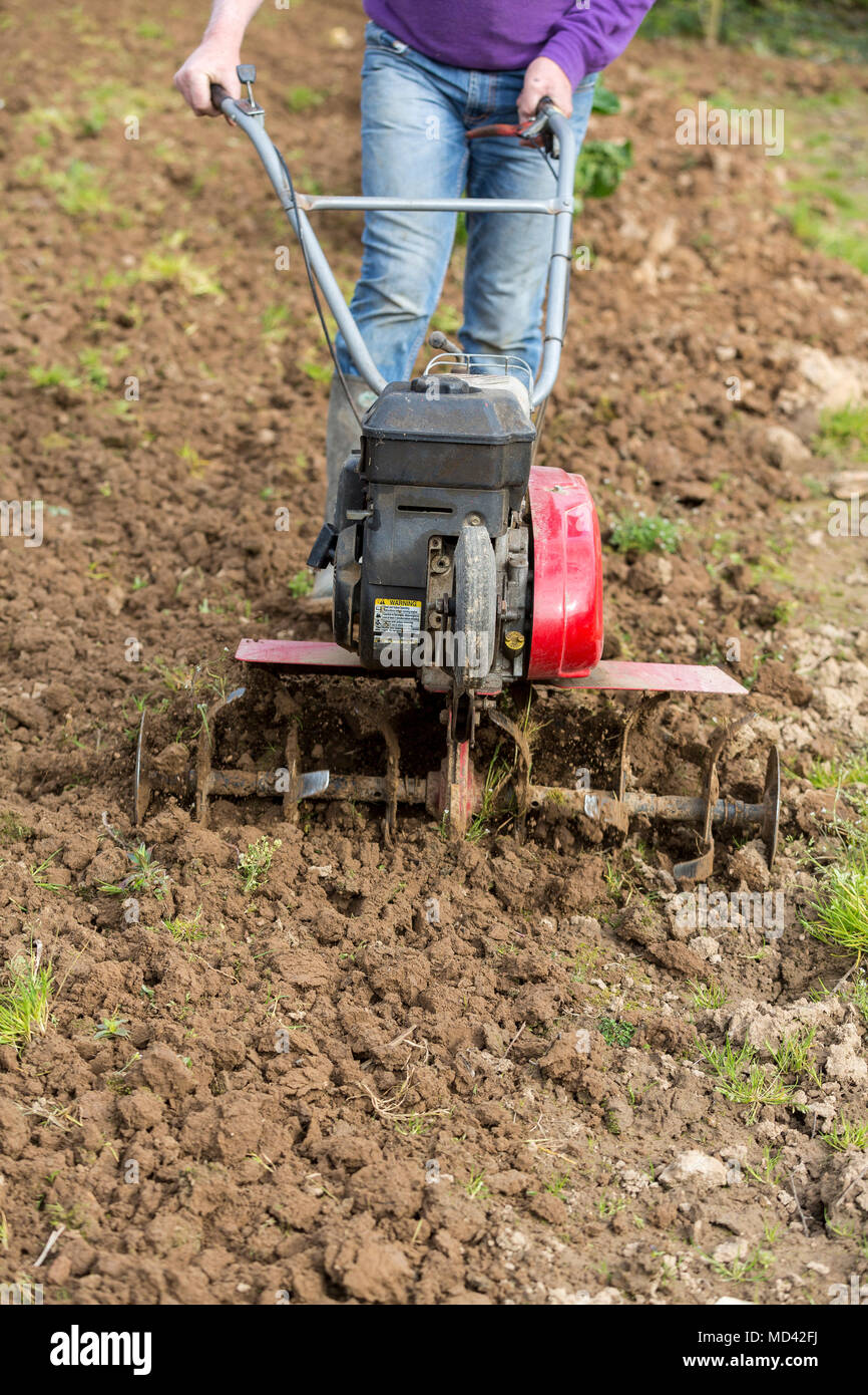 Senior Landwirt Gärtner im Garten arbeitet mit rototiller, Deichsel