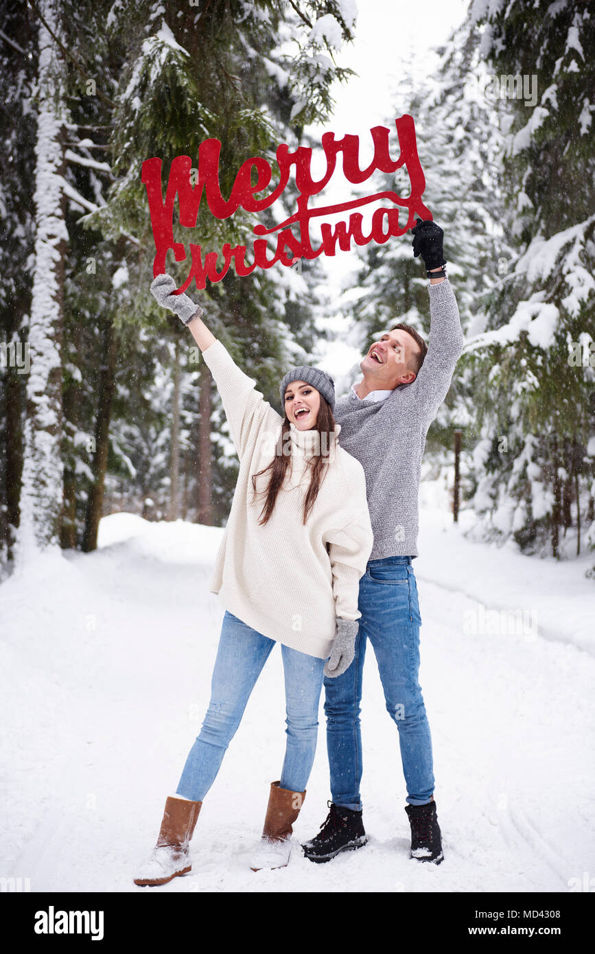 Junges Paar mit Frohe Weihnachten Wörter im Schnee Stockfoto