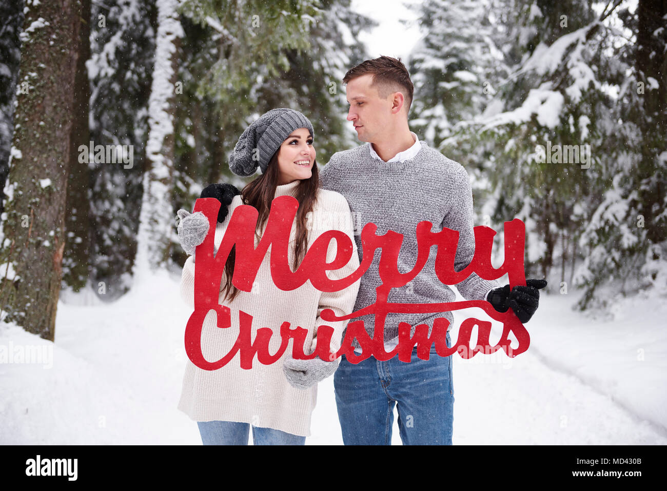 Junges Paar mit Frohe Weihnachten Wörter im Schnee Stockfoto