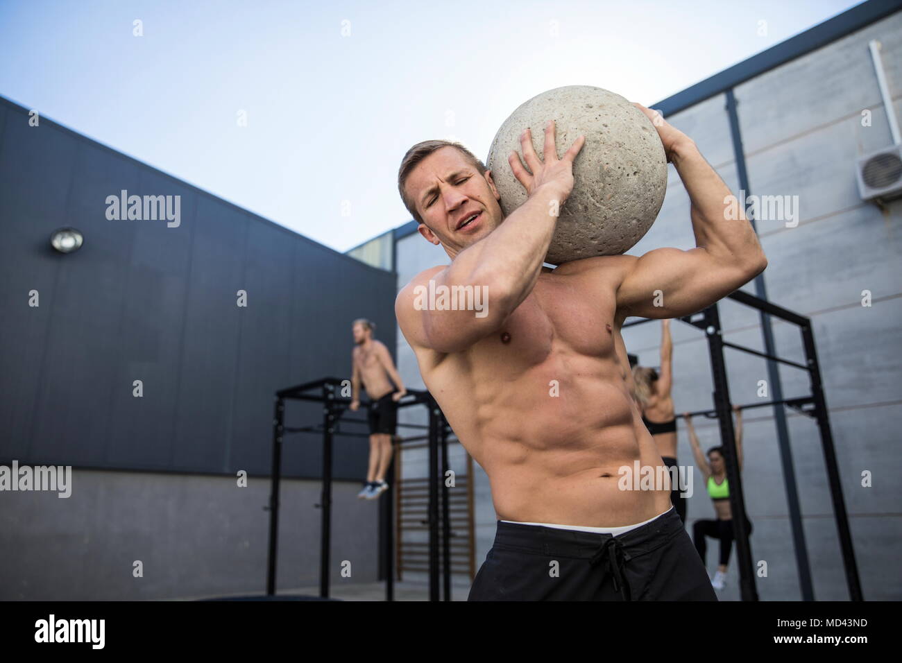 Vier Leute trainieren im Fitnessraum, Mann im Vordergrund, den Einsatz von Atlas Stein Stockfoto