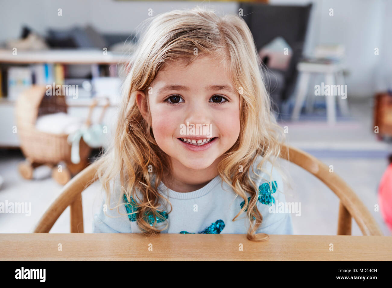 Porträt eines jungen Mädchens, das Sitzen am Tisch, lächelnd Stockfoto