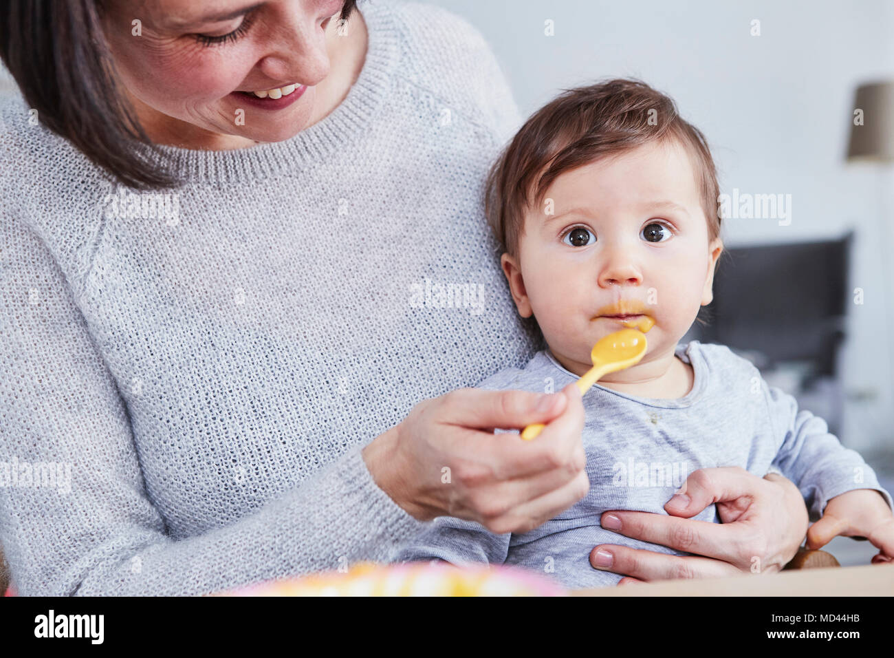 Mutter spoon-feeding baby Tochter Stockfoto