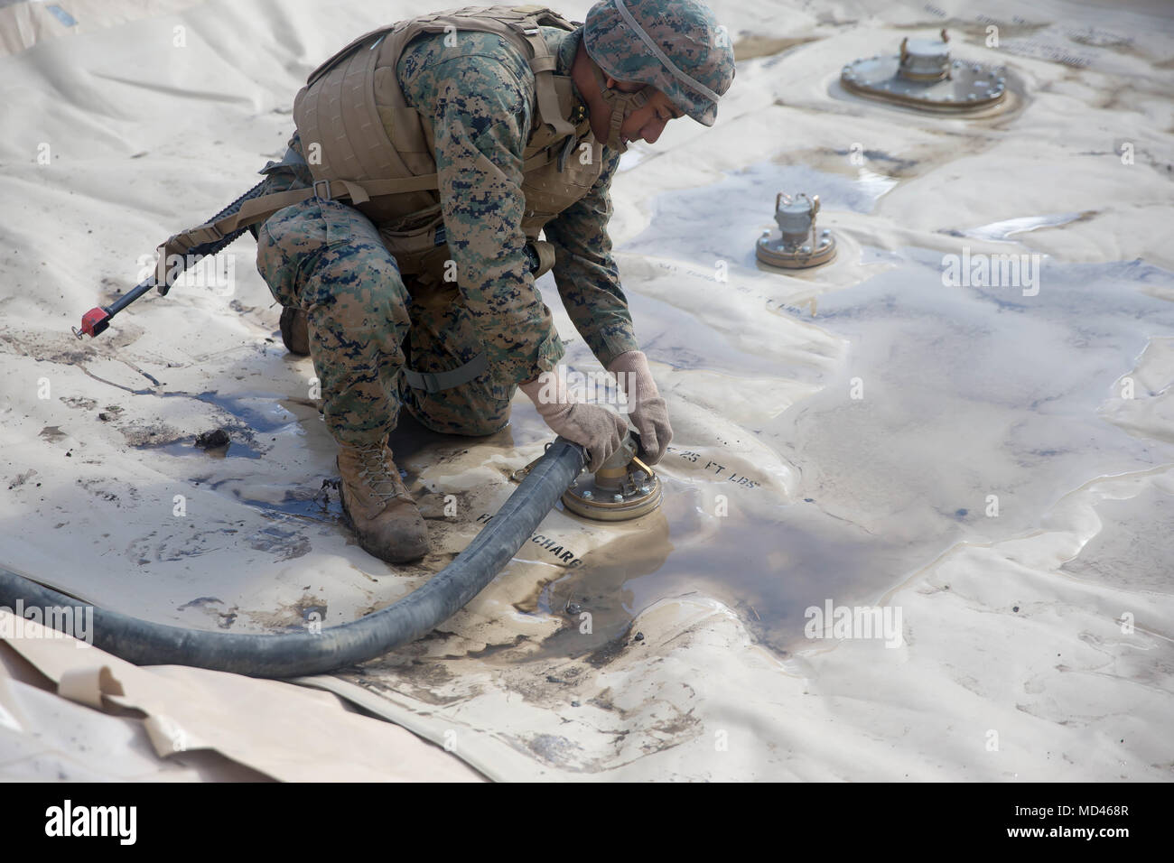Us Marine Lance Cpl. Carlos Effio, bilk Kraftstoff Spezialist mit 7. Techniker Bataillon, 1. Marine Logistik Gruppe, legt eine Saugleitung auf einem 3.000 Liter Kraftstoff Beutel in Camp Pendleton, Kalifornien, USA, 17. März 2018. Die Saugleitung ist speziell mit Metallhalterung im Schlauch die Leitung zusammenbricht während des Gebrauchs zu verhindern. (U.S. Marine Corps Foto von Sgt. Rodion Zabolotniy) Stockfoto
