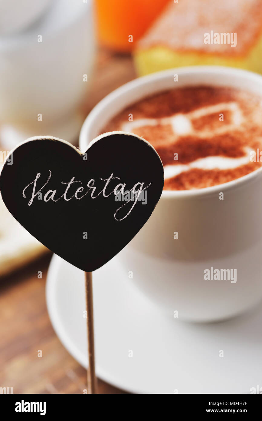 Schild mit Text Vatertag, Vatertag in Deutsch und einer Tasse Cappuccino mit einer Brille und einem Schnurrbart bilden das Gesicht eines Mannes gezeichnet Stockfoto