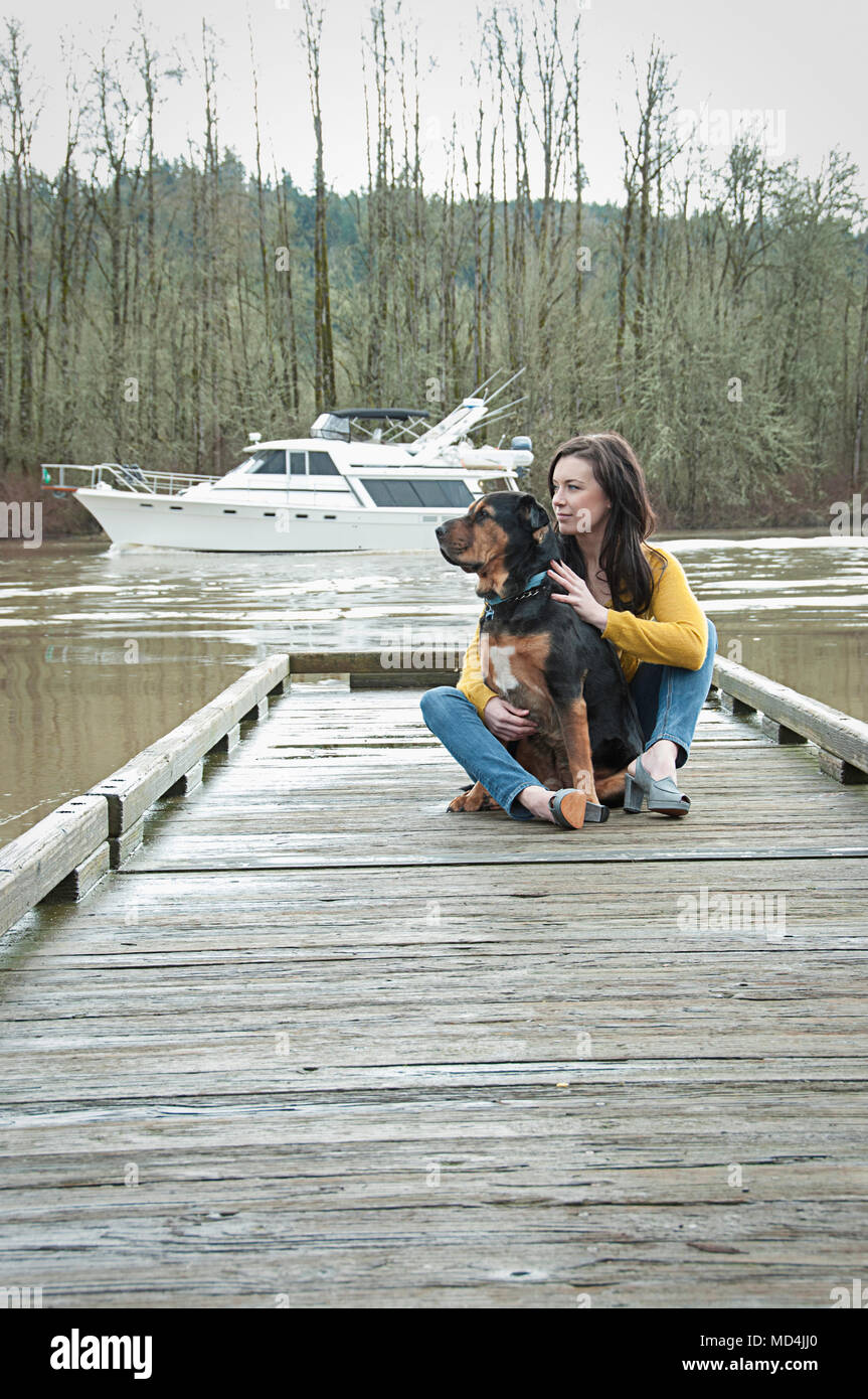 Eine Frau und ihr Hund auf einem Dock in Oregon sitzen. Stockfoto