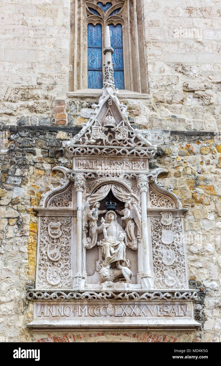 Bas Relief der König von Ungarn Matthias in voller Rüstung sitzt mit seinen Füßen auf einem Löwen. Engel halten eine Krone auf sein Haupt. Auf beiden Seiten Wappen. Stockfoto