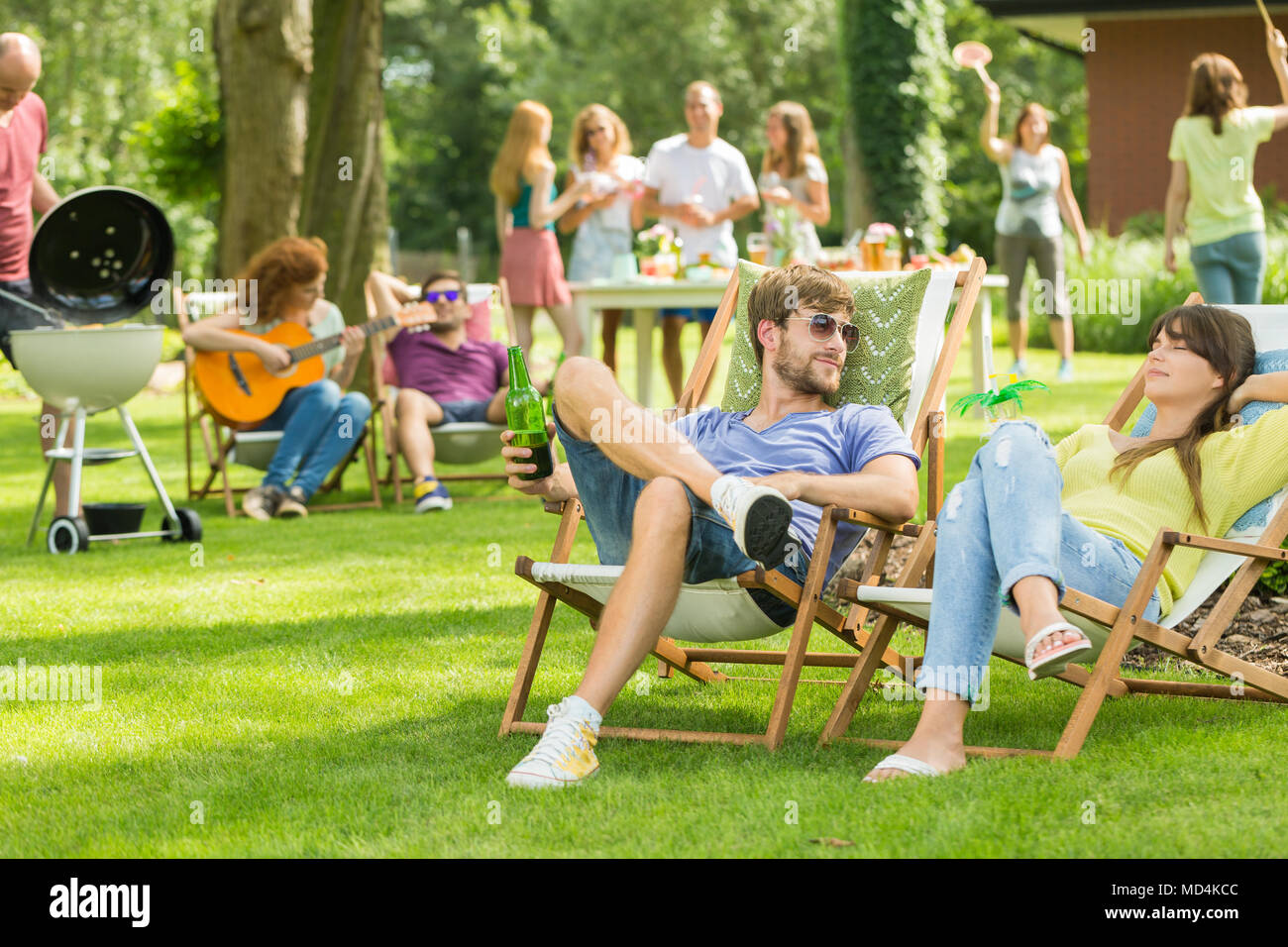 Junge Freunde in Grill Picknick in der Natur, Gitarre spielen, spielen Badminton, sonnigen Sommertag im Freien genießen. Stockfoto