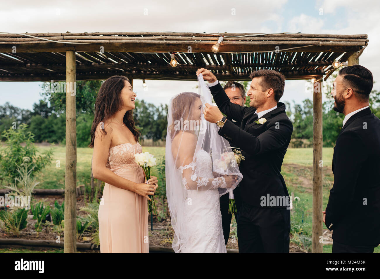 Hübscher Bräutigam anheben Bridal Veil schöne Braut zu küssen. Paar mit einer freien Trauung. Braut und Bräutigam über Küssen nach dem wedd Stockfoto