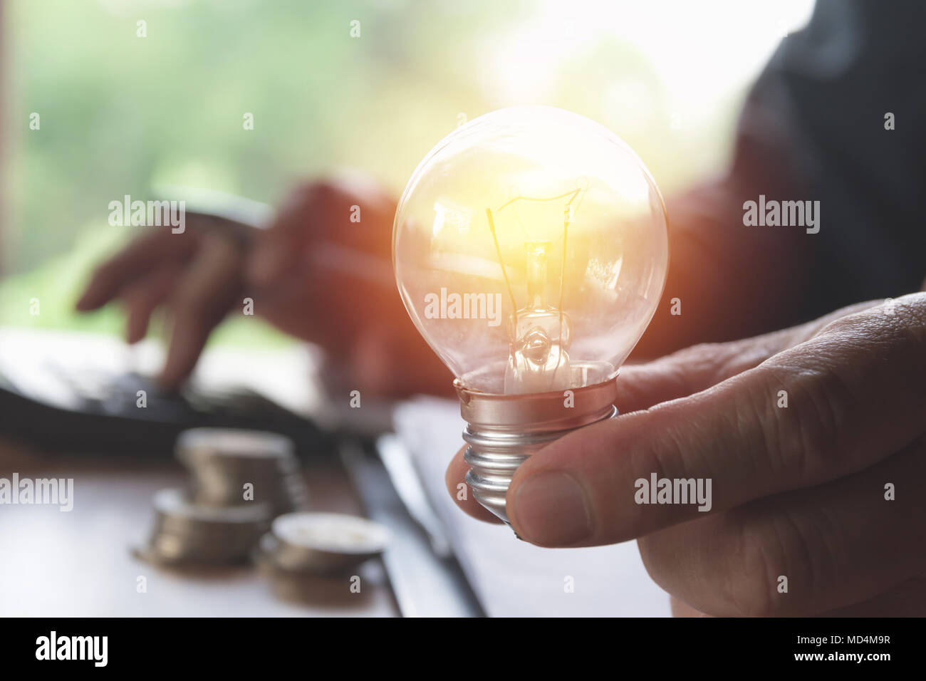 Hand, die Glühbirnen leuchten und mit Taschenrechner. Idee, Kreativität und Energie sparen mit Energiesparlampen Konzept. Stockfoto