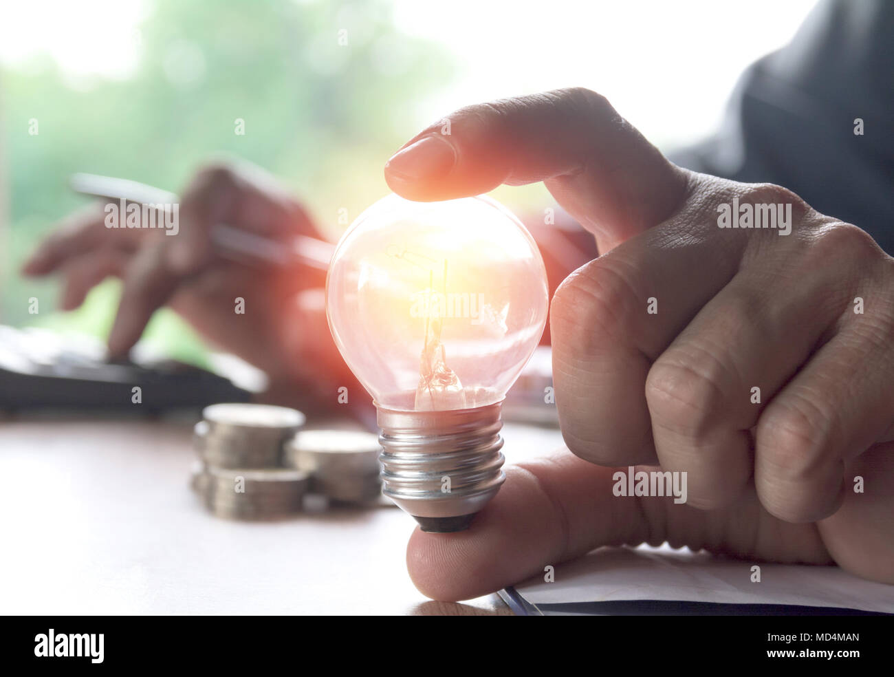 Hand, die Glühbirnen leuchten und mit Taschenrechner. Idee, Kreativität und Energie sparen mit Energiesparlampen Konzept. Stockfoto