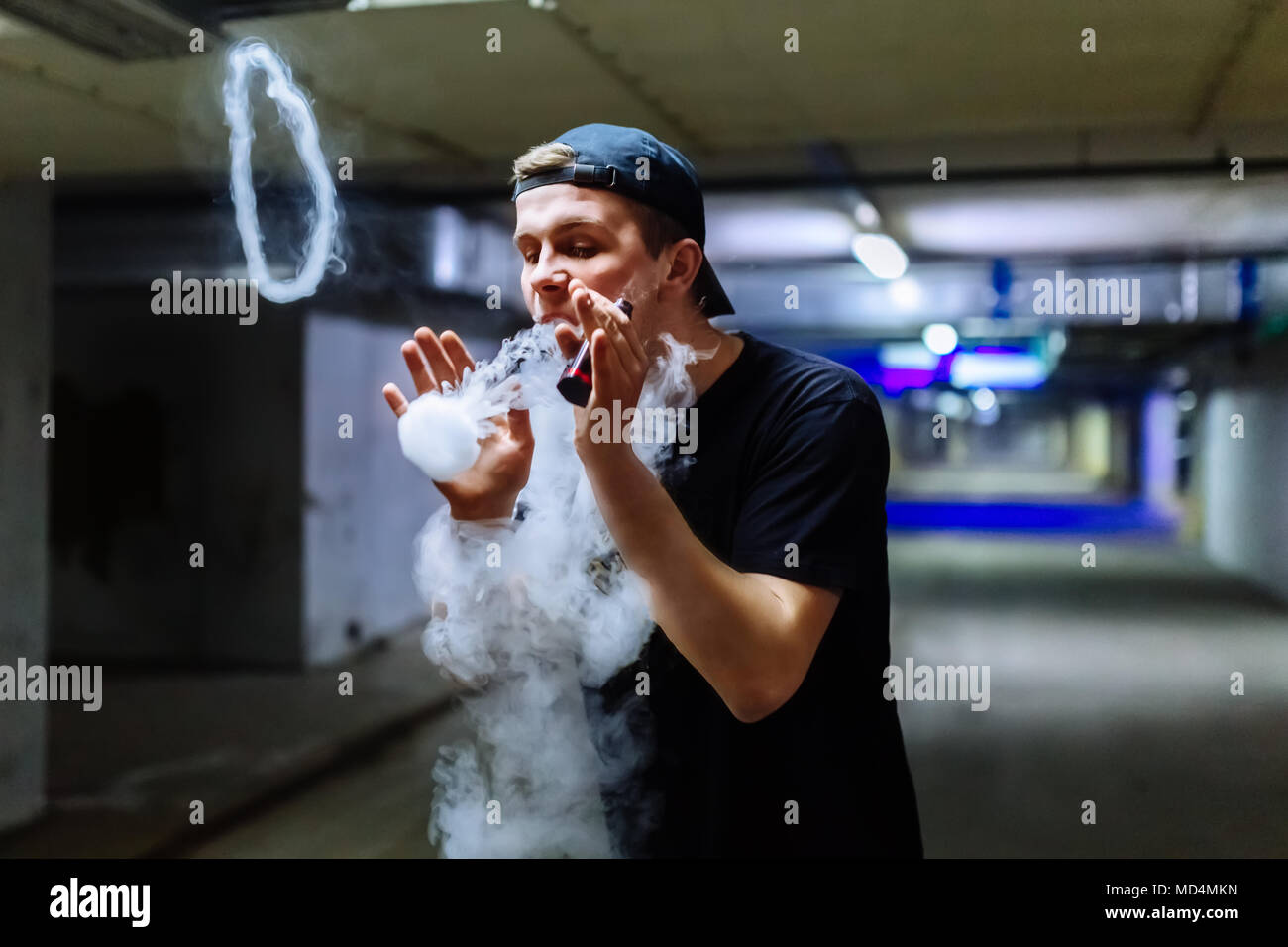 Mann in Gap Rauch eine elektronische Zigarette Ausführen verschiedener Art vaping Tricks Stockfoto