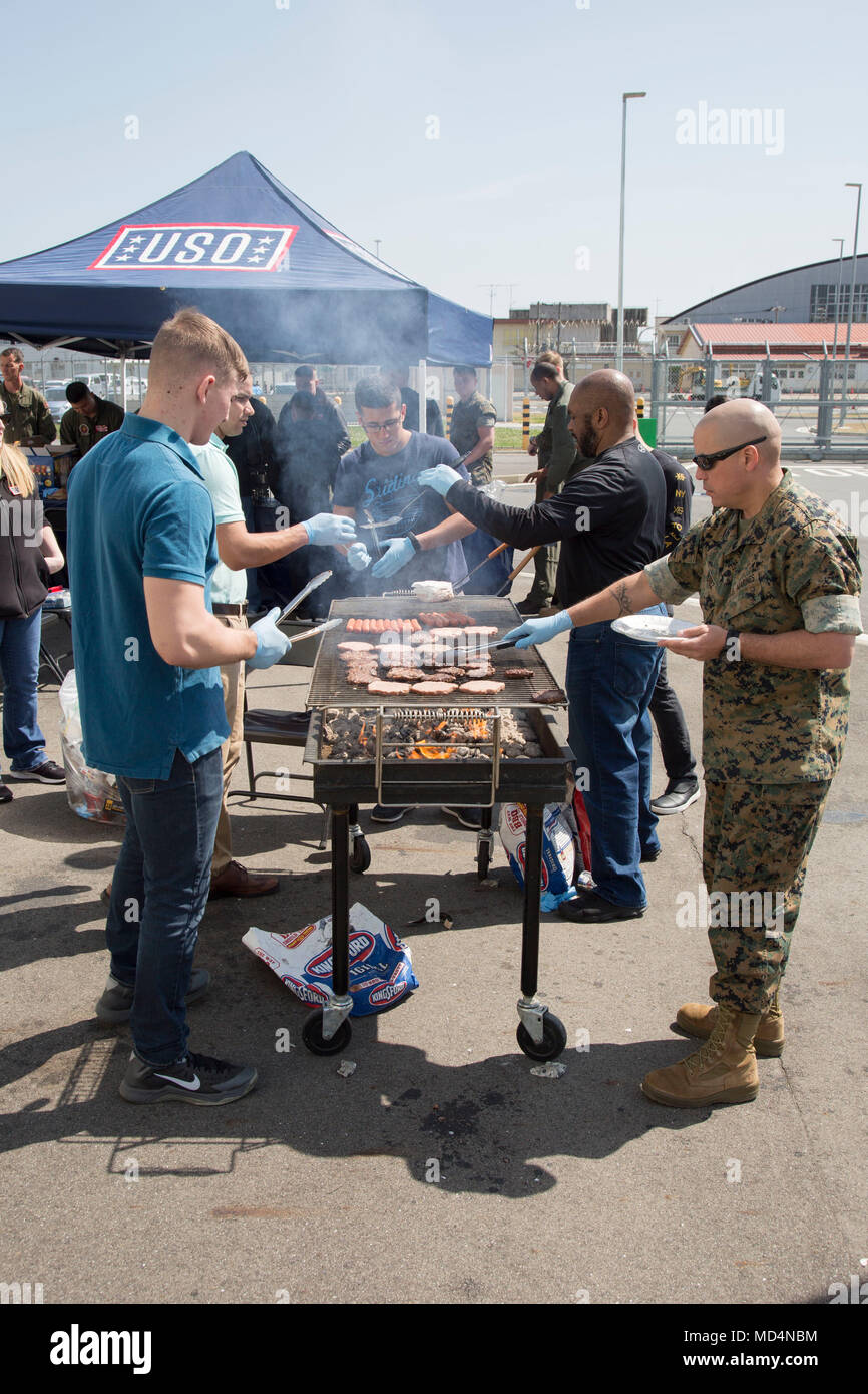 United Service Organizations ist eine gemeinnützige Organisation, die das US-Militär durch Moral- und Sozialprogramme weltweit unterstützt. Das Archivbild dokumentiert Freiwillige, die zusammen mit der Führung der Marine Aviation während eines Barbecue der Marine Corps Air Station Iwakuni, Japan, am 23. März 2018, organisiert für Marine Aerial Refueler Transport Squadron 152 und zugehörige Wartungseinheiten, Nahrung zubereiten. Stockfoto