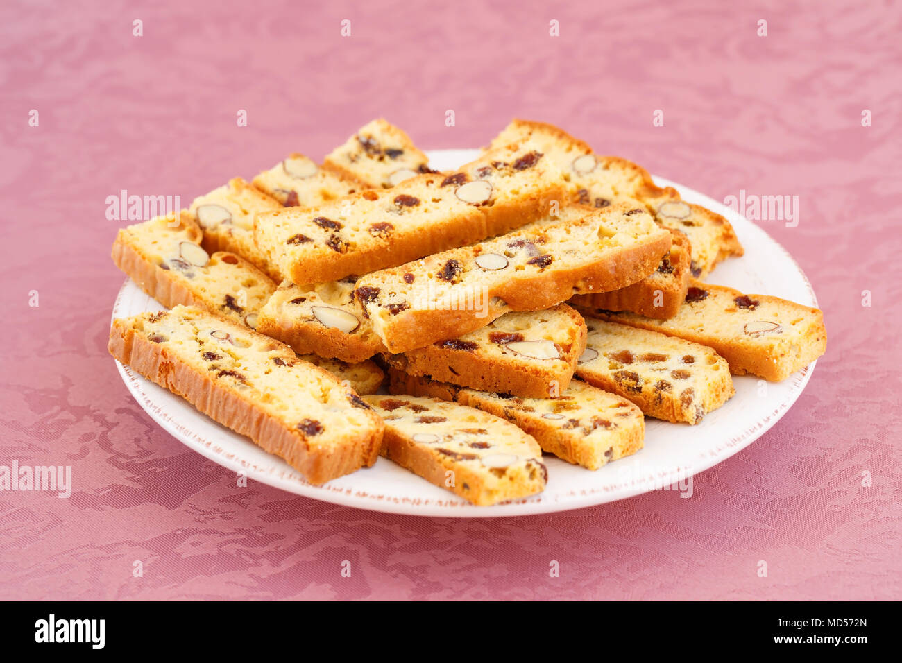 Cracker mit Nüssen und Rosinen in der Platte auf rosa Hintergrund Tuch. Stockfoto