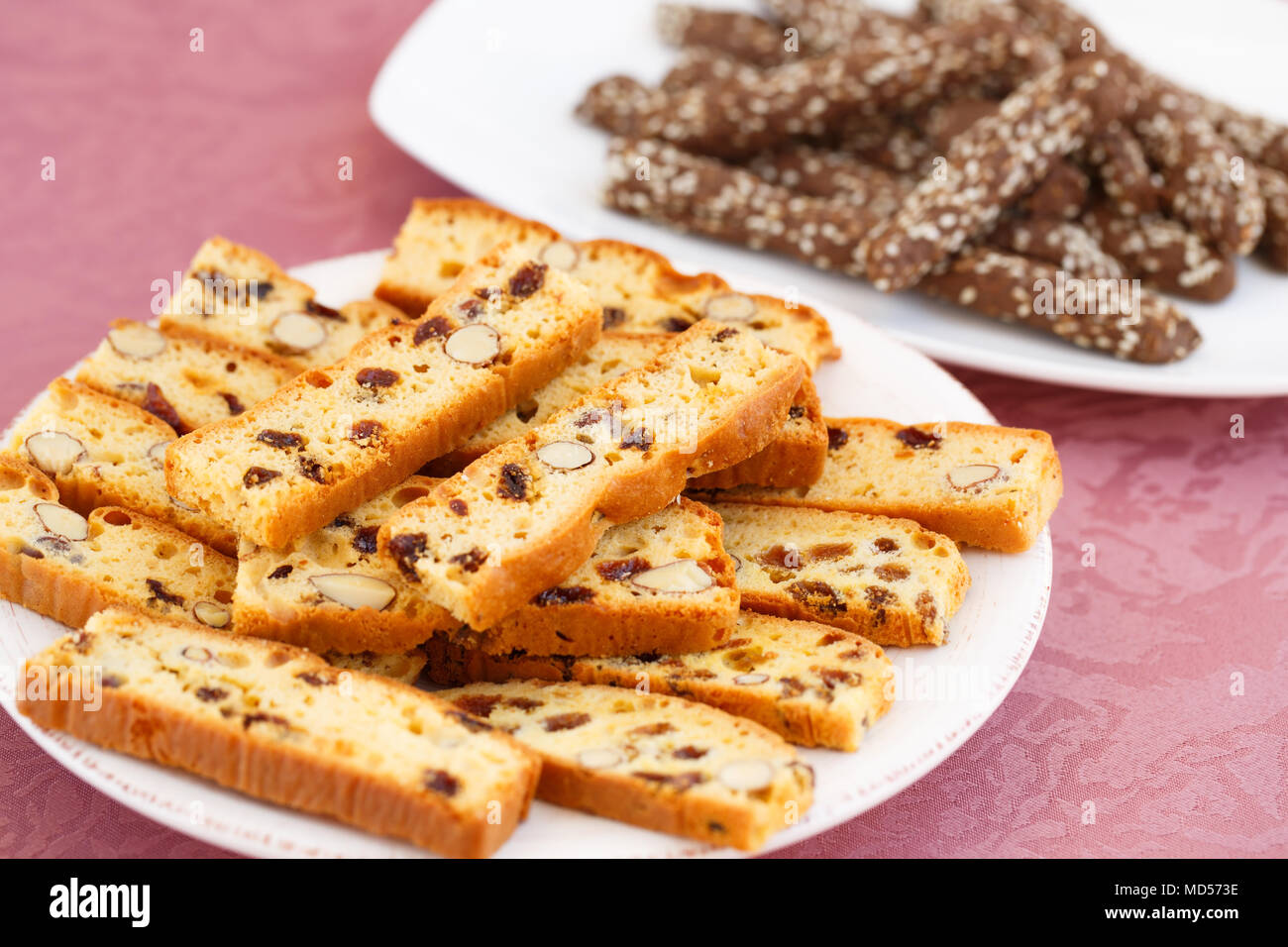 Johannisbrot Kekse und Cracker mit Nüssen und Rosinen in Platten auf rosa Hintergrund Tuch. Stockfoto