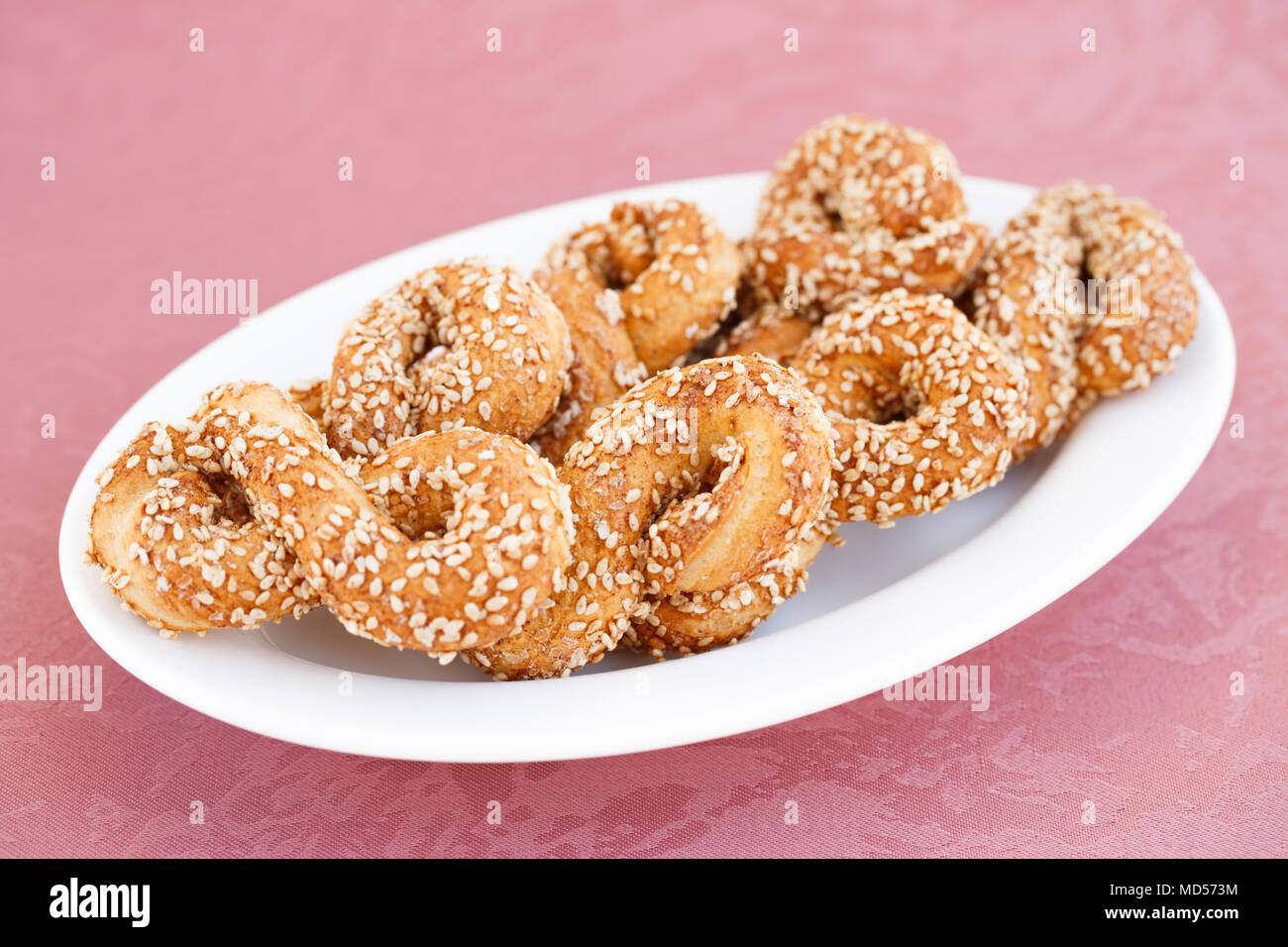 Kräcker mit Sesam in der Platte auf rosa Hintergrund Tuch. Stockfoto