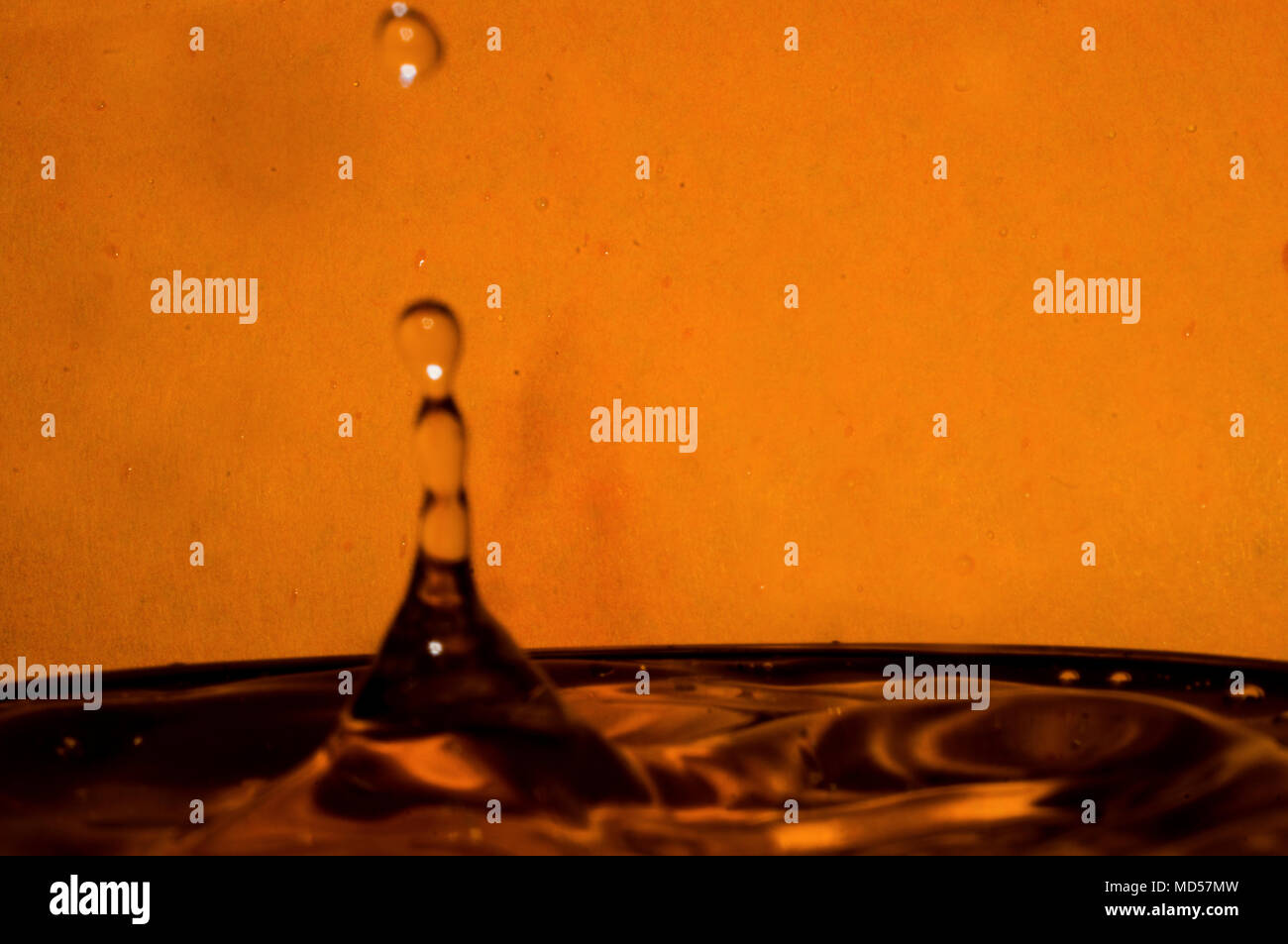 Wassertropfen spritzen an den orangefarbenen Hintergrund Stockfoto