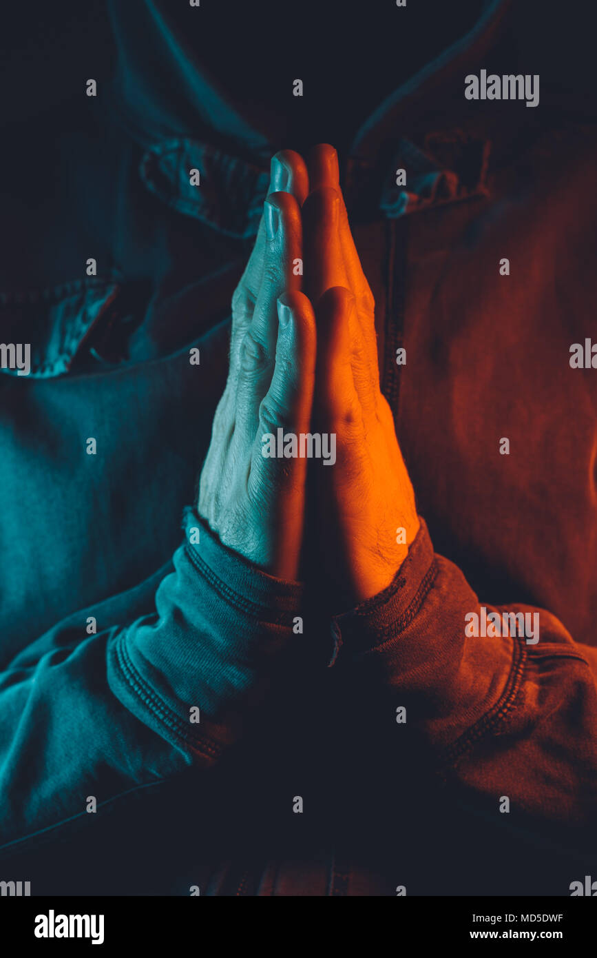 Betende Hände von religiösen Menschen, Rot und Blau beleuchtete low-key-Bild Stockfoto