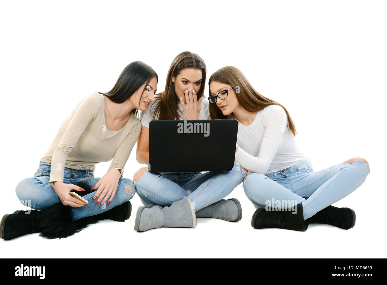 Drei Mädchen auf dem Boden sitzend, im Schneidersitz, Laptop Stockfoto