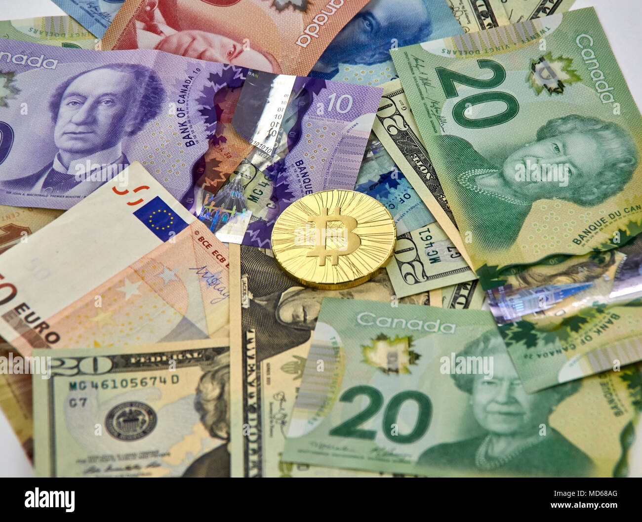 MONTREAL, KANADA - 10. MÄRZ 2018: Bitcoin cryptocurrency gold coin und Logo auf Euro, US-Dollar, kanadische Dollar Banknoten. Stockfoto