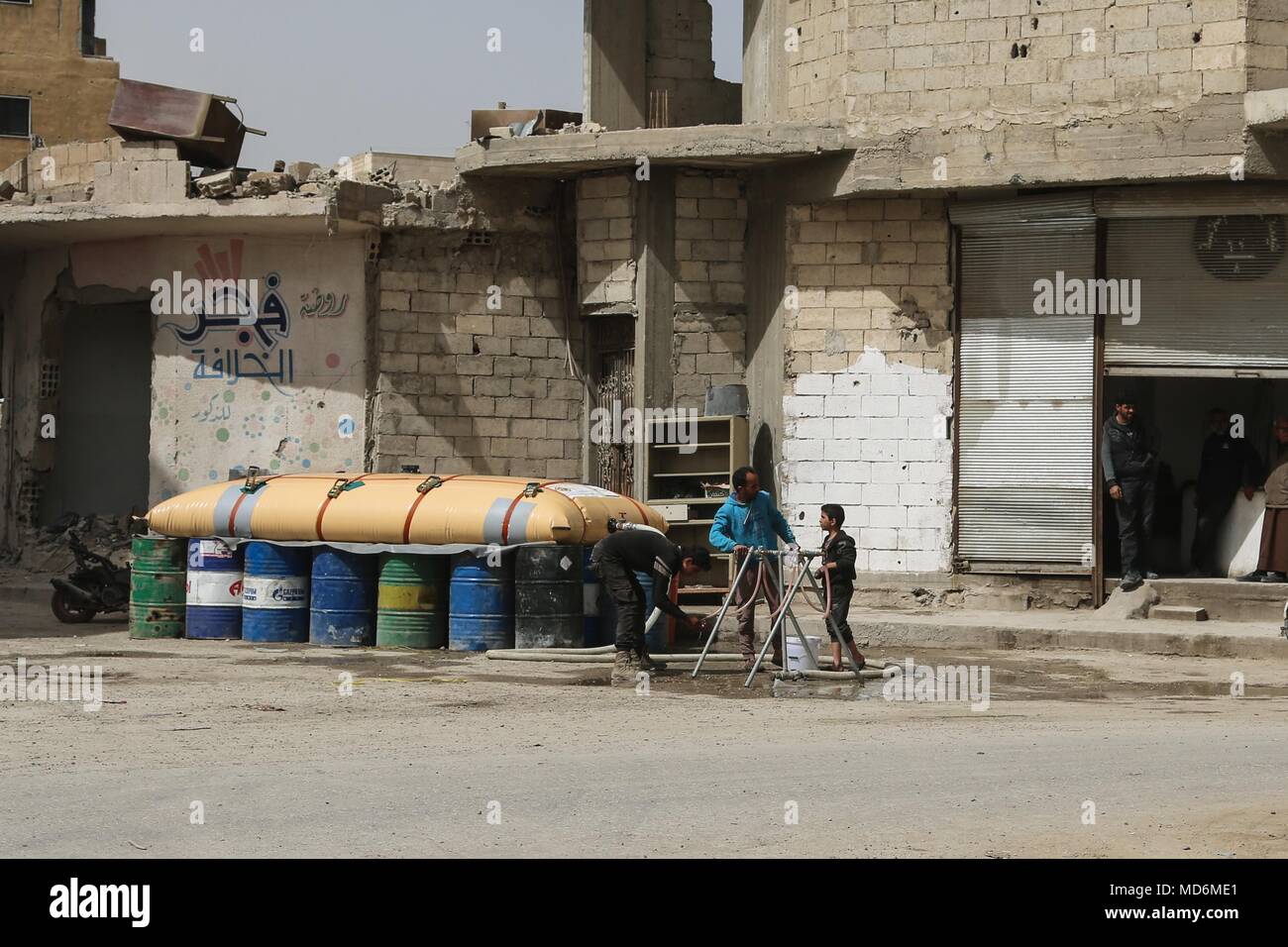 Bewohner mit einem in der Nähe Wasser Blase frisches Wasser in Raqqa, Syrien, 19. März 2018 zu erwerben. Seit der Niederlage der ISIS in Raqqa, die Koalition ist die Unterstützung der Prioritäten der raqqa der Zivilgesellschaft die kritische Infrastruktur und Dienstleistungen, die in der ganzen Stadt wieder herzustellen und die Umgebung. CJTF-OIR ist die globale Koalition zu besiegen ISIS im Irak und in Syrien. (U.S. Armee Foto von Sgt. Travis Jones) Stockfoto