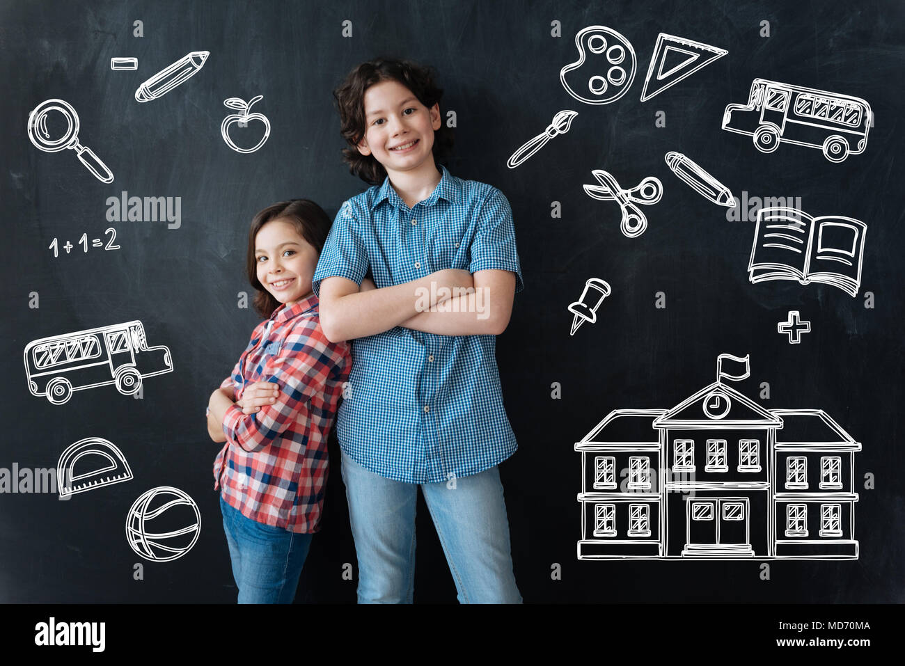 Glückliche Kinder stehen mit ihren verschränkten Armen und wartet für die Schule Stockfoto