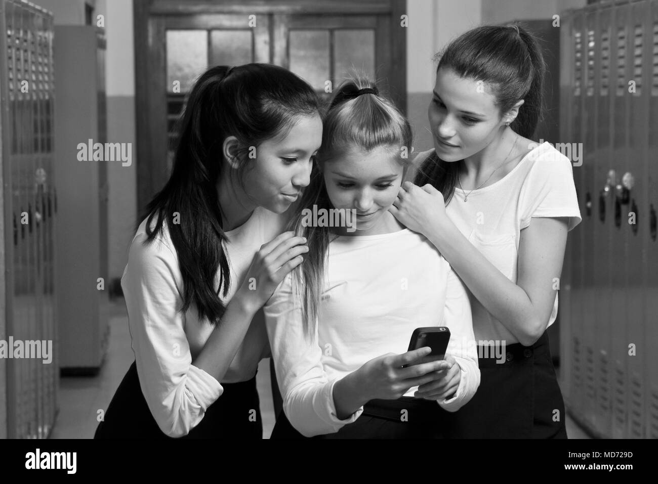 Drei glückliche High School Mädchen haben sie Spaß mit Ihrem Mobiltelefon Stockfoto