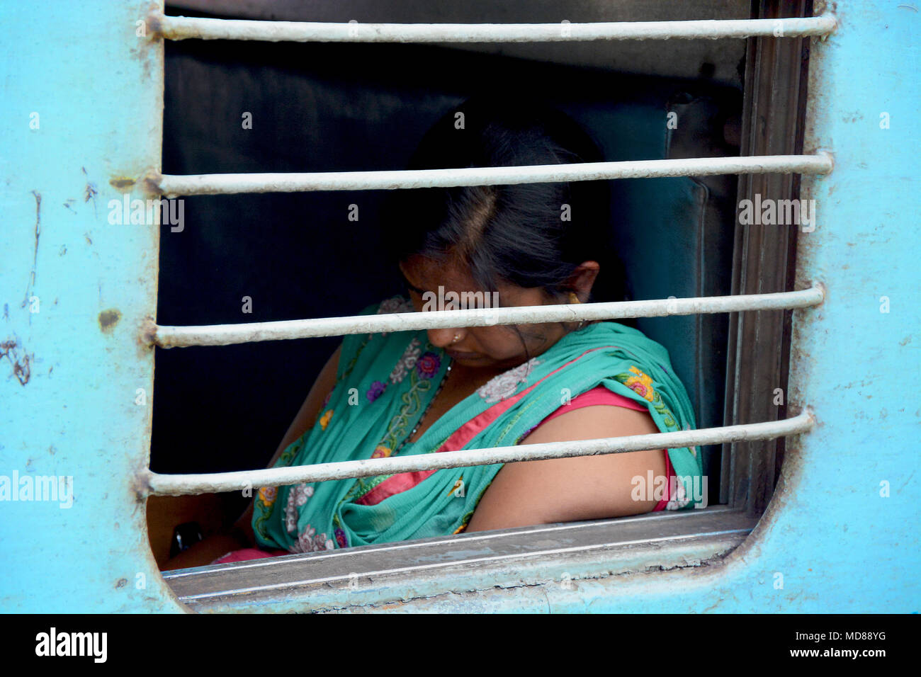 Frau aslee durch die vergitterten Fenster eines indischen Waggon gesehen Stockfoto