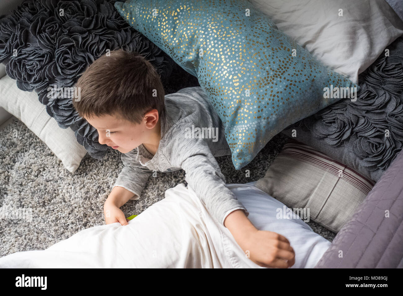 Neugierige kleine Junge liegend auf Bett Stockfoto