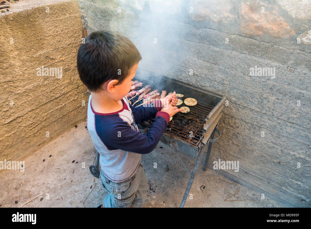 Little Boy kochen Kebab und Aubergine auf Grill, Heraklion, Griechenland Stockfoto
