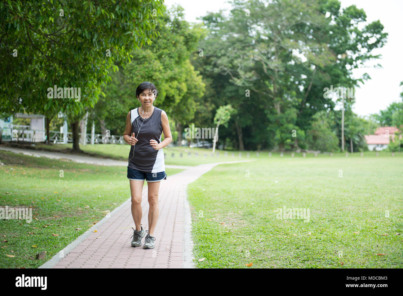 Vorderansicht der älteren Frau joggen durch den Park Stockfoto